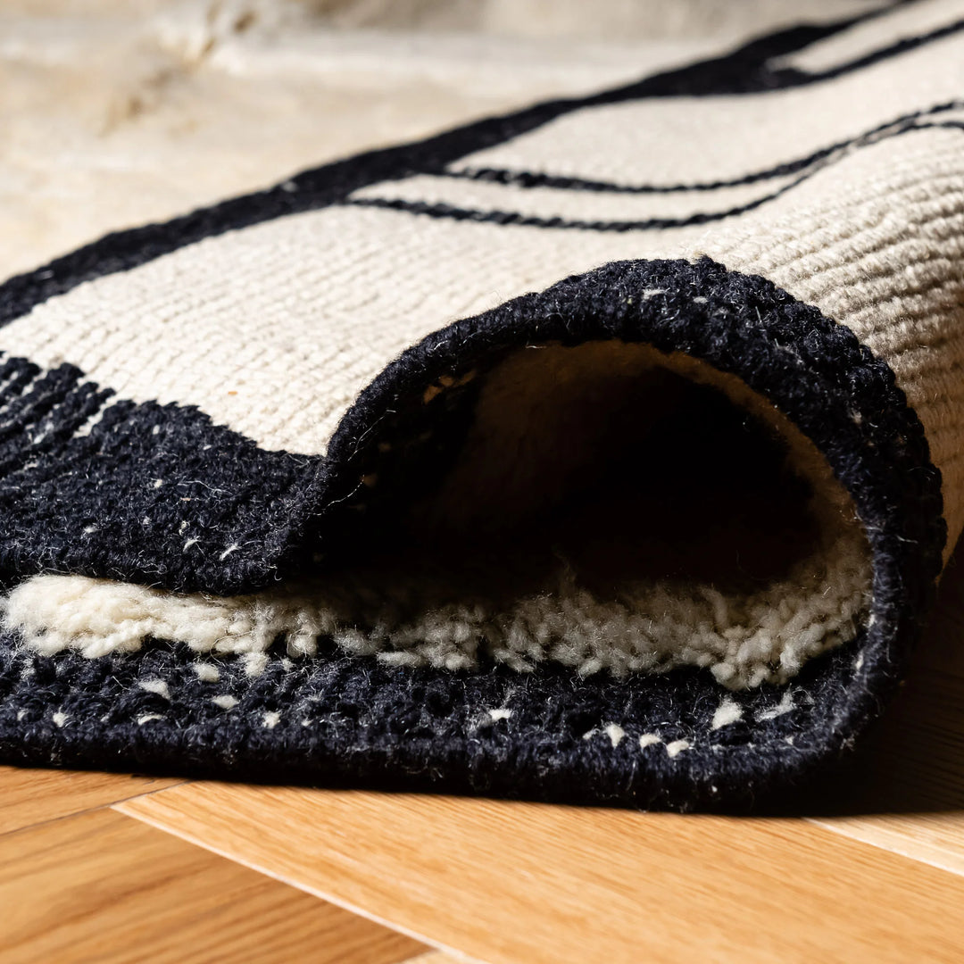 Abstract cream and black Moroccan wool rug with diamond pattern, showcasing texture and craftsmanship, perfect for modern interiors.