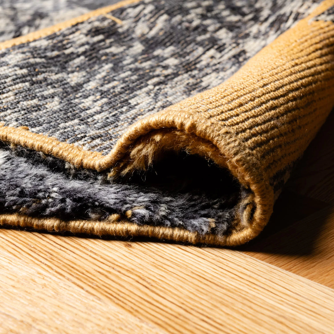 Close-up of yellow Moroccan wool rug with abstract patterns and earthy tones on wooden floor.