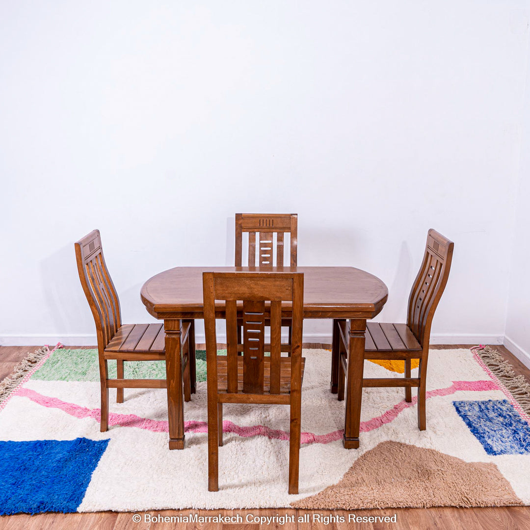 Wooden dining set on colorful handmade Moroccan wool shag rug with abstract design and vibrant colors.