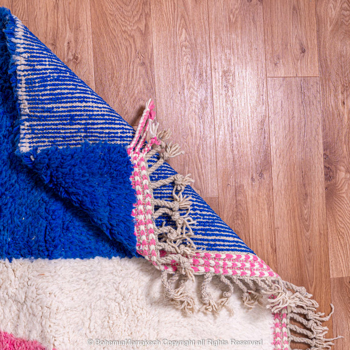 Handmade Moroccan wool shag rug with colorful abstract design in blue, pink, and ivory, showcasing traditional craftsmanship.