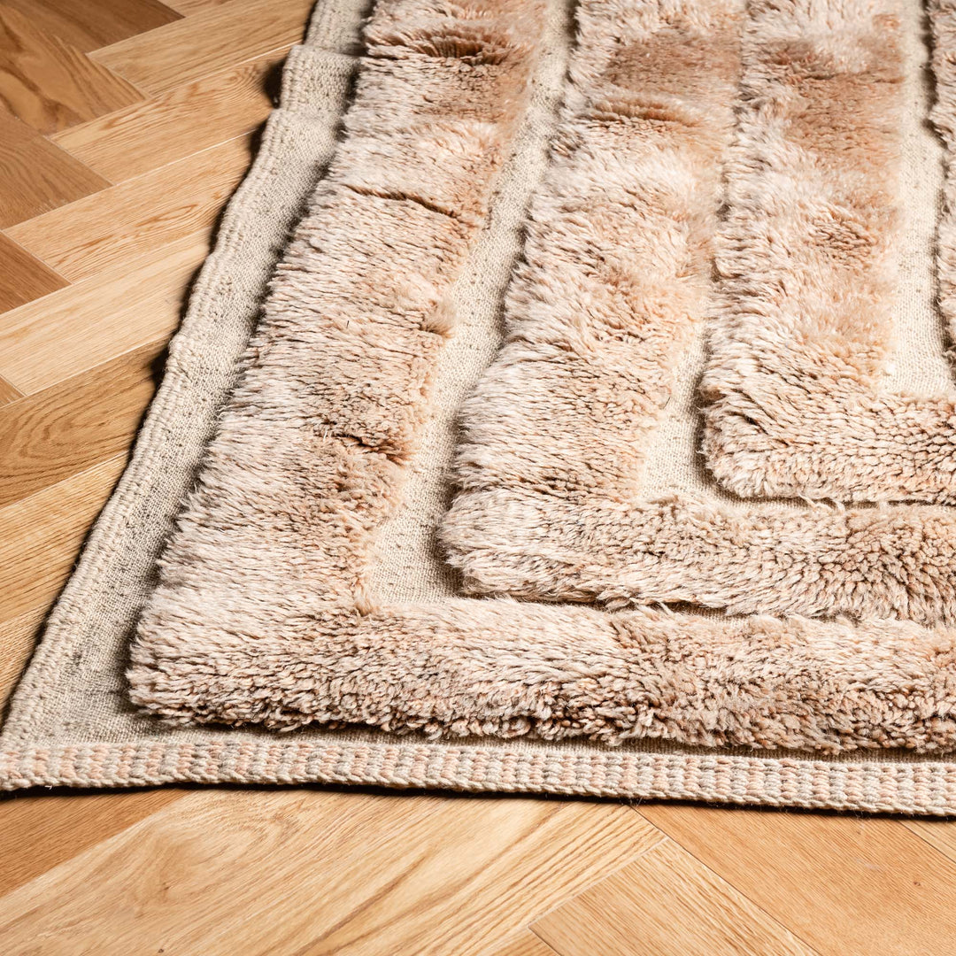 Beige Beni Mrirt Moroccan wool rug with high-pile texture on hardwood floor, handcrafted by Berber artisans.