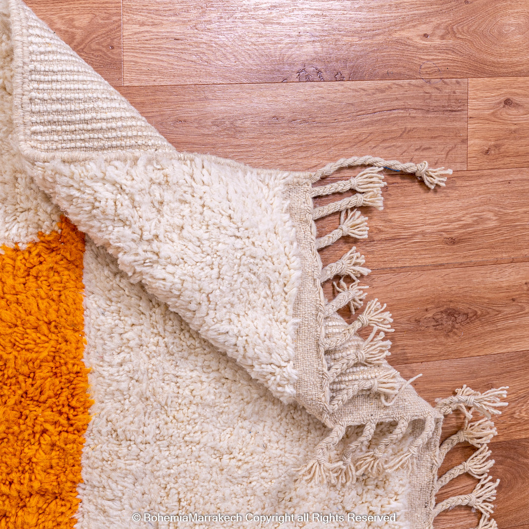 Handmade Moroccan wool rug with abstract orange and beige block design on cream background