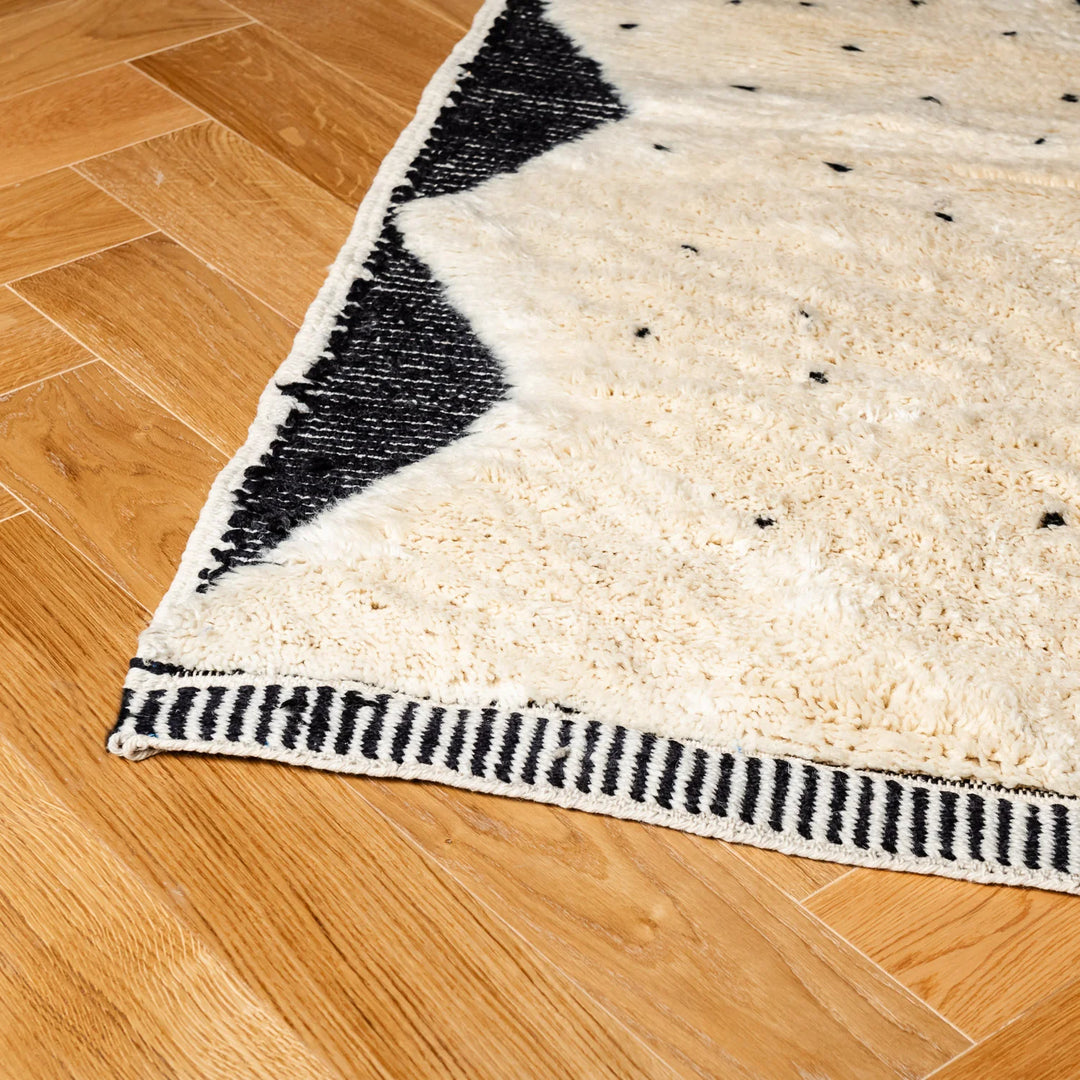 Traditional Beni Ourain Moroccan rug with diamond and dotted pattern, wool texture on wood floor, tribal Berber design.