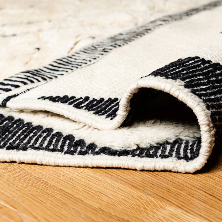 Beni Ourain Moroccan rug with diamond and dotted pattern, black and white design, detailed view on wooden floor.