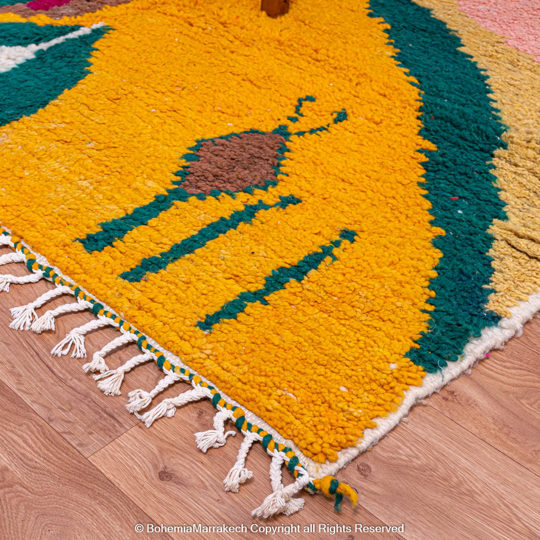 Handmade Moroccan wool rug with geometric patterns in yellow, green, and pink, featuring a plush texture, on wooden floor