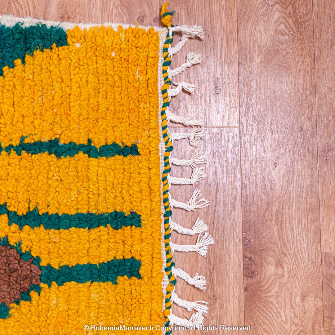 Close-up of a vibrant yellow and green Beni Ourain Moroccan shag rug on wooden flooring.