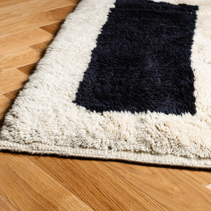 Black and white abstract Moroccan wool rug with geometric design on hardwood floor, perfect for contemporary interiors.