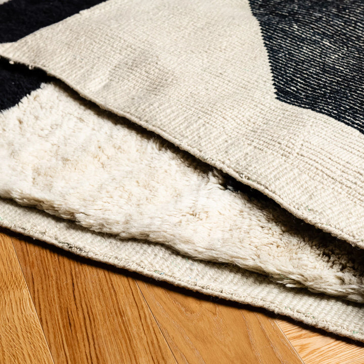 Close-up of a black and white abstract Moroccan rug with geometric patterns, showcasing its plush wool texture and hand-knotted craftsmanship.