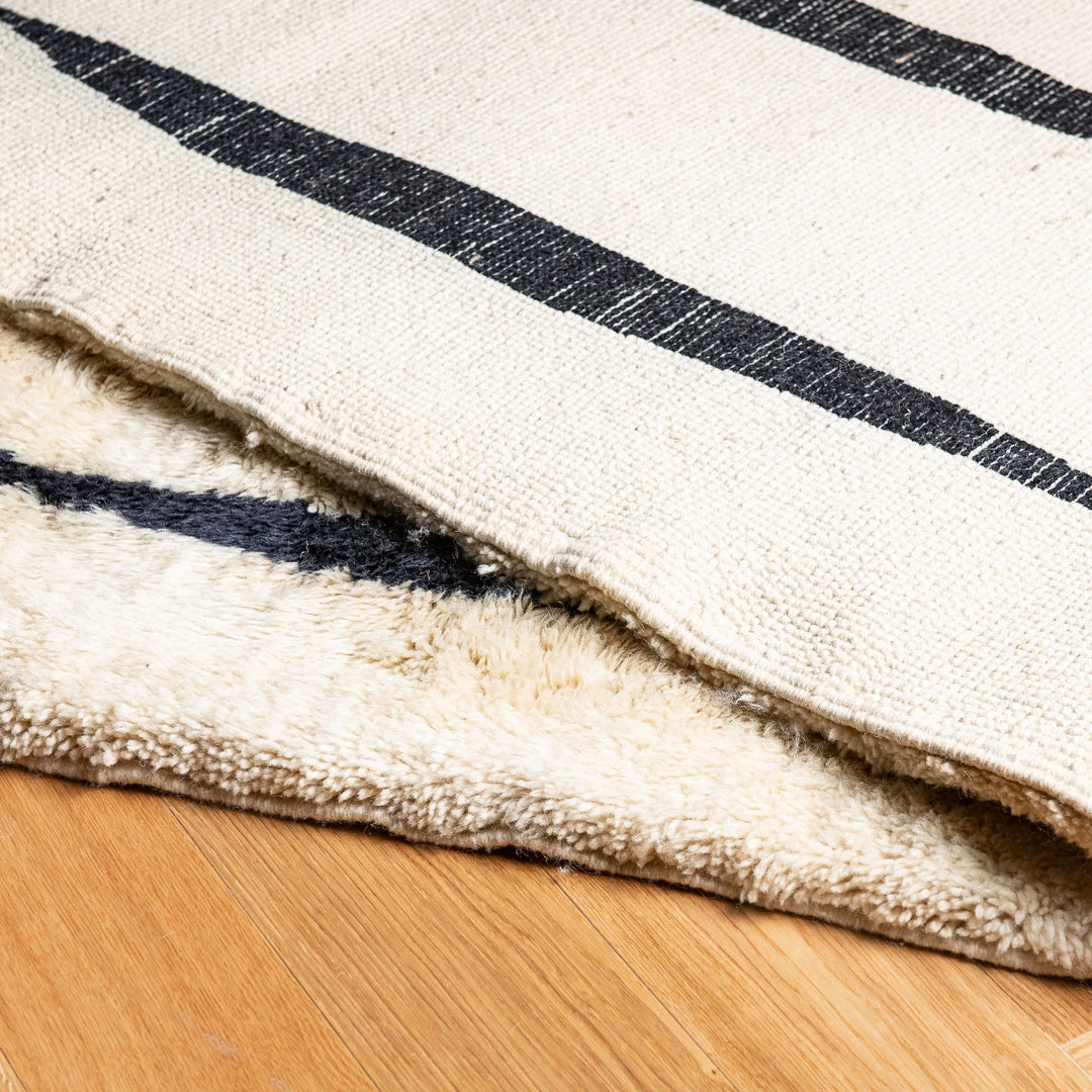 Black and white Moroccan wool rug with vertical stripes, handcrafted Berber style, showcasing soft texture. Perfect for modern interiors.