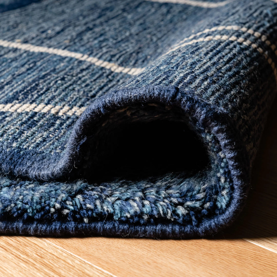 Close-up of Blue Moroccan Beni Mrirt Rug with ivory geometric lines, showcasing wool texture on wooden floor.
