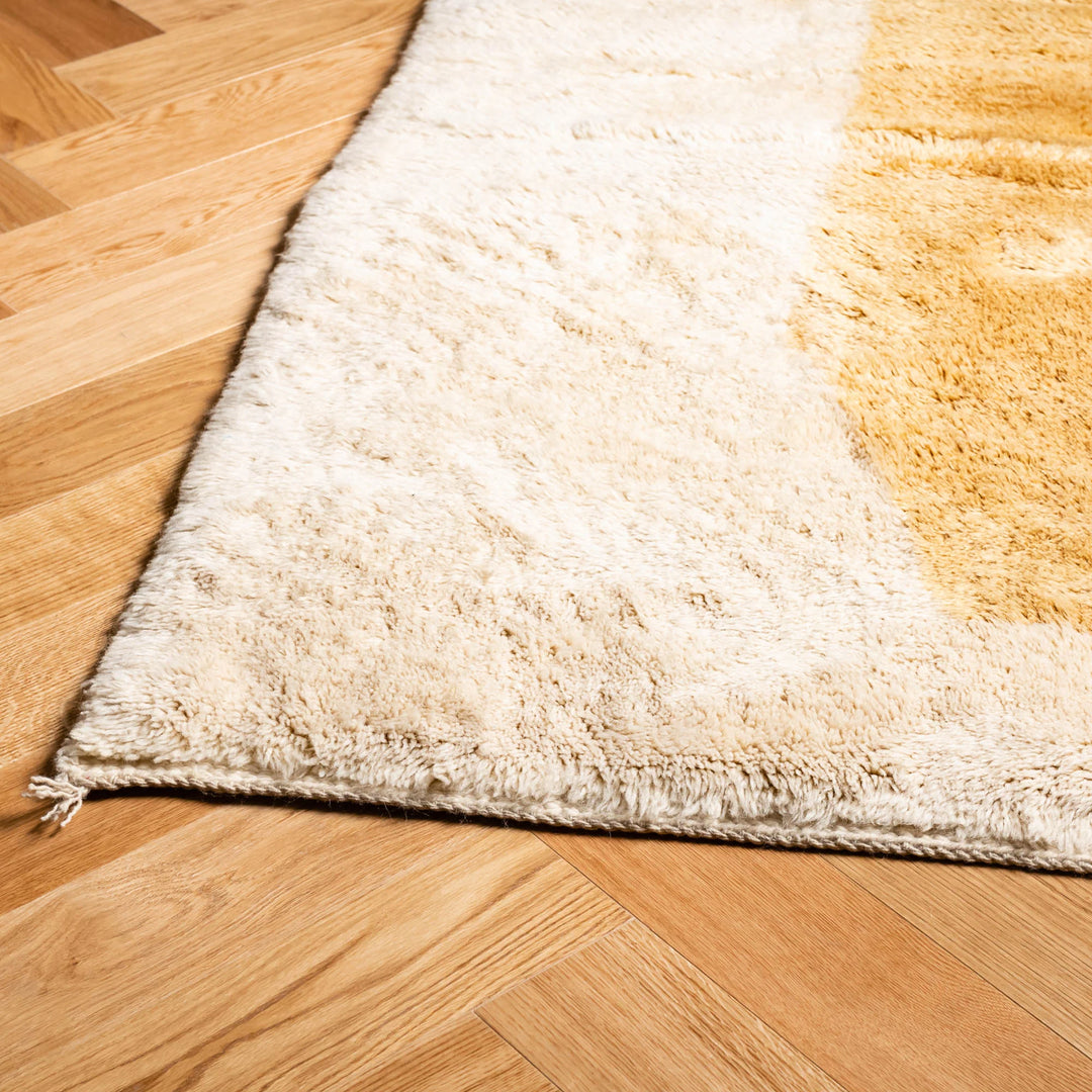 Close-up of a plush Moroccan Berber rug showcasing creamy wool with mustard tones, handwoven by artisans from Morocco.
