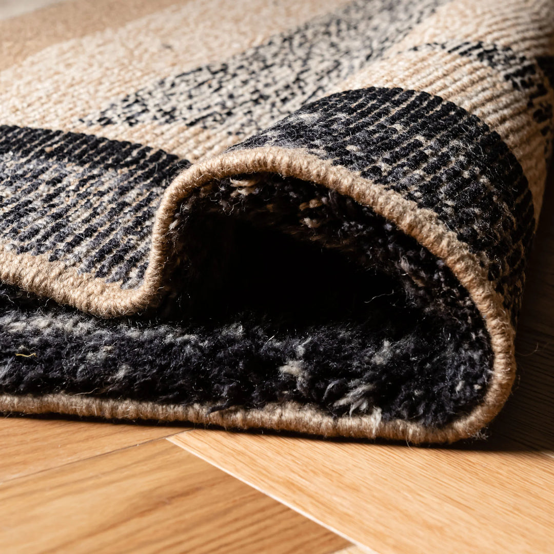 Handmade Moroccan wool rug with bold geometric patterns in black and beige, showcasing plush texture and artistic elegance.