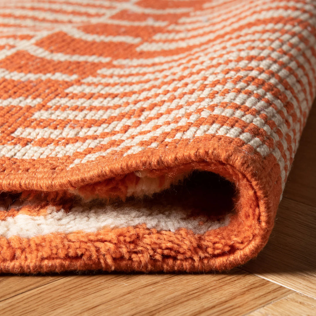 Close-up of bold orange Moroccan rug with tribal zigzag pattern, handcrafted with Berber techniques, ideal for vibrant interiors.