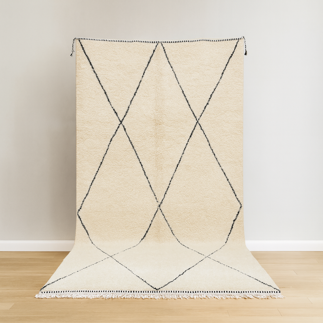 Beige rug with black geometric pattern on a wooden floor and light-colored wall background