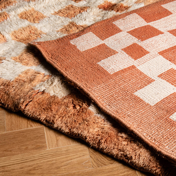 Checkered Moroccan rug with shag finish, showcasing Beni Mrirt design on wood floor. Perfect for traditional or modern decor.