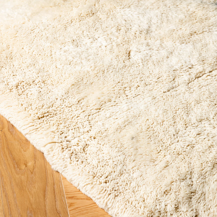 Close-up of Classic Diamond Beni Mrirt Rug, handmade Moroccan wool rug, showcasing ivory wool texture on wooden floor.