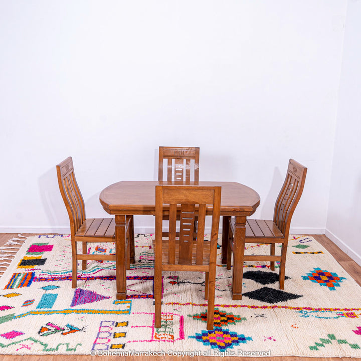 Colorful Azilal Moroccan rug under wooden dining table set.