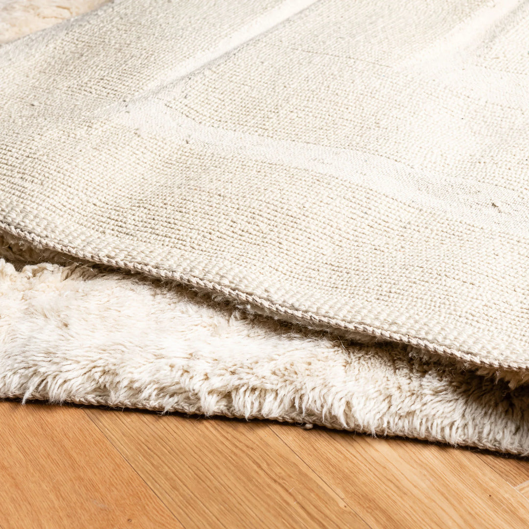 Close-up of Cream Geometric Beni Mrirt Rug on wooden floor, showcasing its plush texture and handmade Moroccan design.
