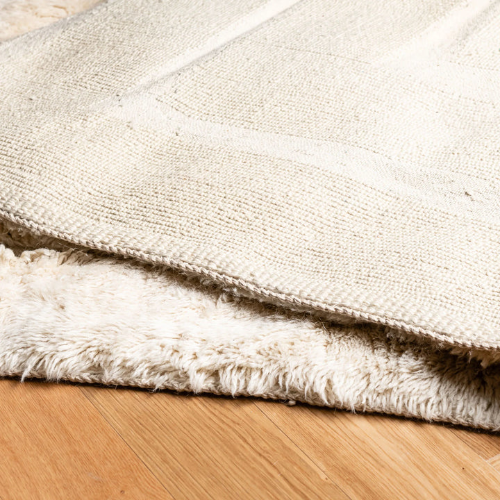 Close-up of Cream Geometric Beni Mrirt Rug on wooden floor, showcasing its plush texture and handmade Moroccan design.