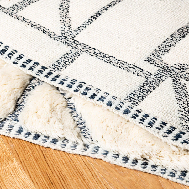 Close-up of a handmade Moroccan wool rug with abstract grid pattern, showcasing plush texture and intricate black linework.