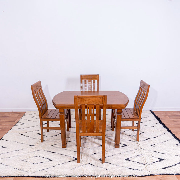 Black and white diamond Moroccan rug under wooden dining table and chairs, featuring traditional Berber design and handmade wool.
