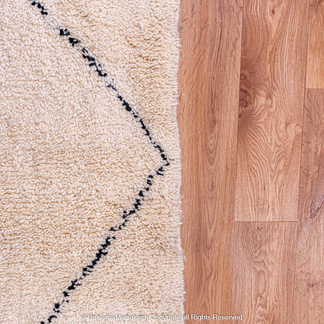 Black and white diamond Moroccan rug on wood floor, handmade wool, minimalist design, traditional Moroccan craftsmanship