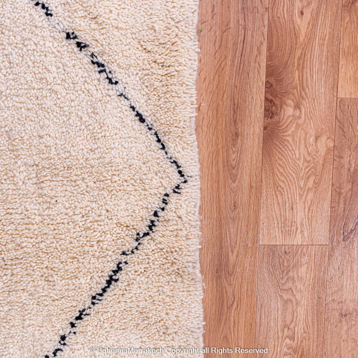 Black and white diamond Moroccan rug on wood floor, handmade wool, minimalist design, traditional Moroccan craftsmanship