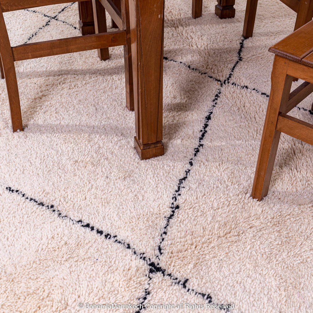 Black and white diamond Moroccan wool rug with minimalist pattern under wooden dining table, handcrafted by Berber artisans.