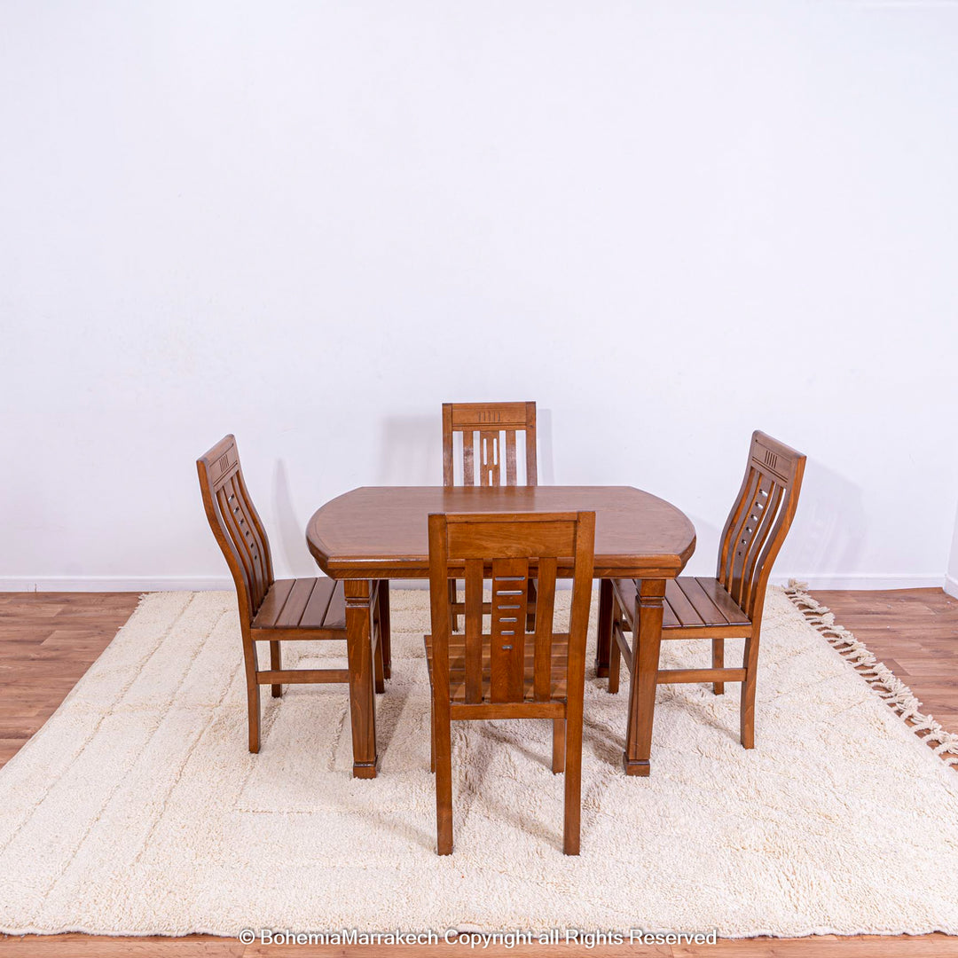 Wooden dining set on cream Moroccan Berber rug with geometric pattern.