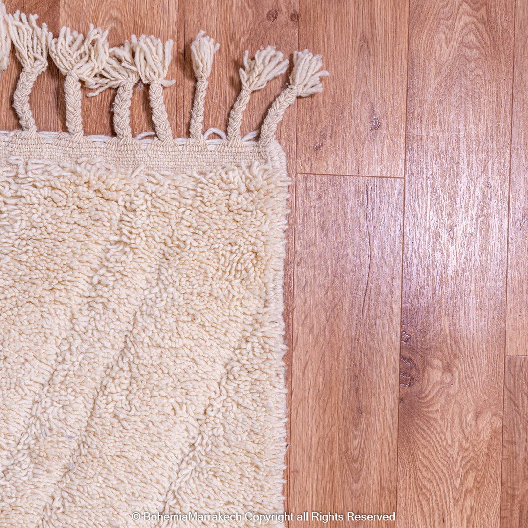 Handmade cream Moroccan Berber wool rug on wooden floor