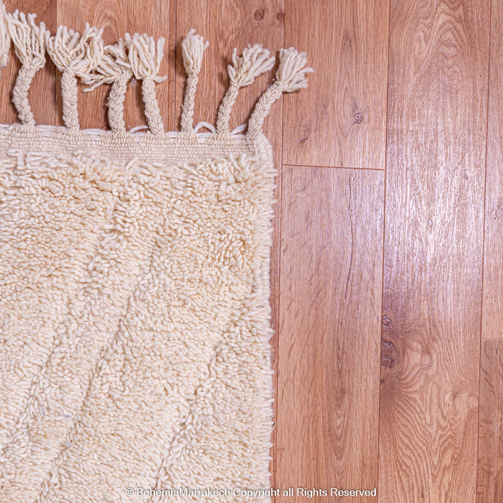 Handmade cream Moroccan Berber wool rug on wooden floor