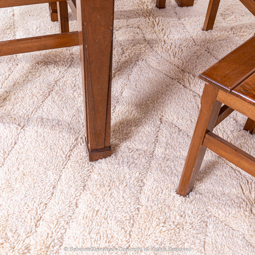 Cream Moroccan Berber wool area rug under wooden dining table and chairs, featuring subtle geometric design.