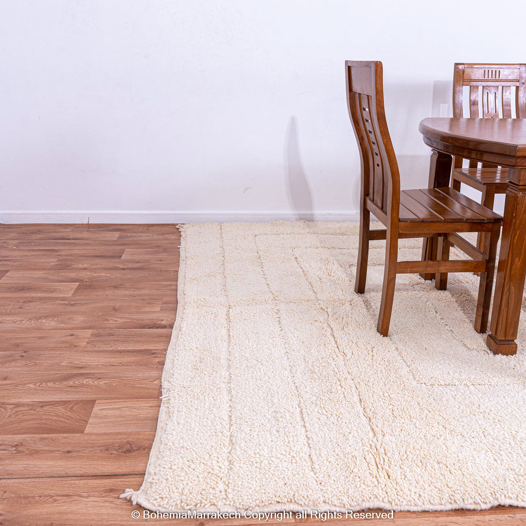 Cream Moroccan Berber rug under dining table, handcrafted wool area rug with subtle geometric lines, complements serene interiors.
