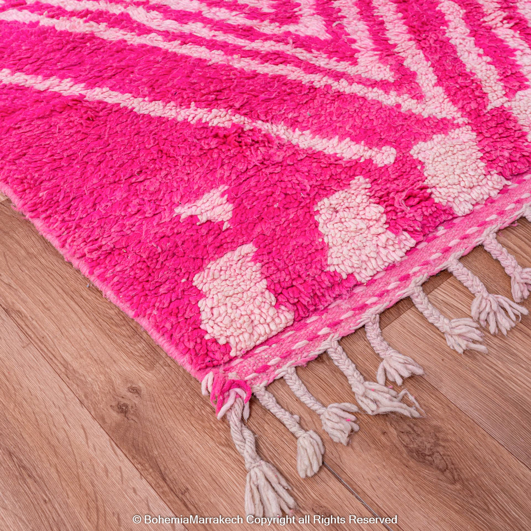 Pink Moroccan Berber wool rug with white diamond motifs on wooden floor