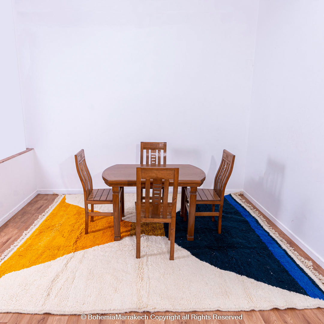 Modern Moroccan wool rug with yellow and navy abstract design under dining table and chairs in a minimalist room.