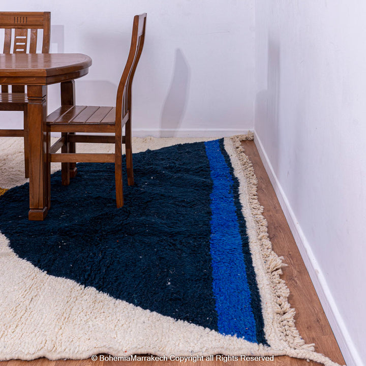 Modern Moroccan wool rug in yellow and navy abstract design under dining table, featuring soft, thick wool and hourglass patterns.