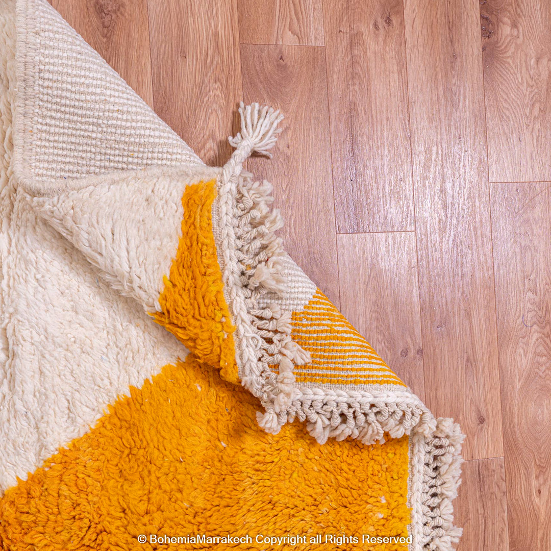 Modern Moroccan wool rug with yellow and cream colors on wooden floor. Handmade traditional Moroccan Berber carpet style.