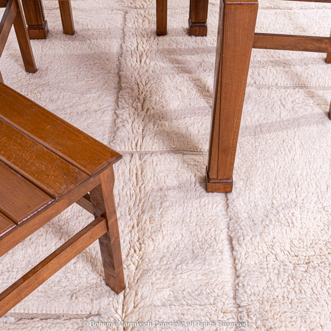 White grid Moroccan wool rug under wooden dining set, modern Beni Ourain style for contemporary decor. Moroccan rug sale.