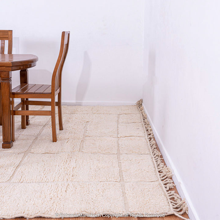 White grid Moroccan wool rug in dining room setting, handmade by Berber artisans, ideal for modern decor. Beni Ourain style rug.