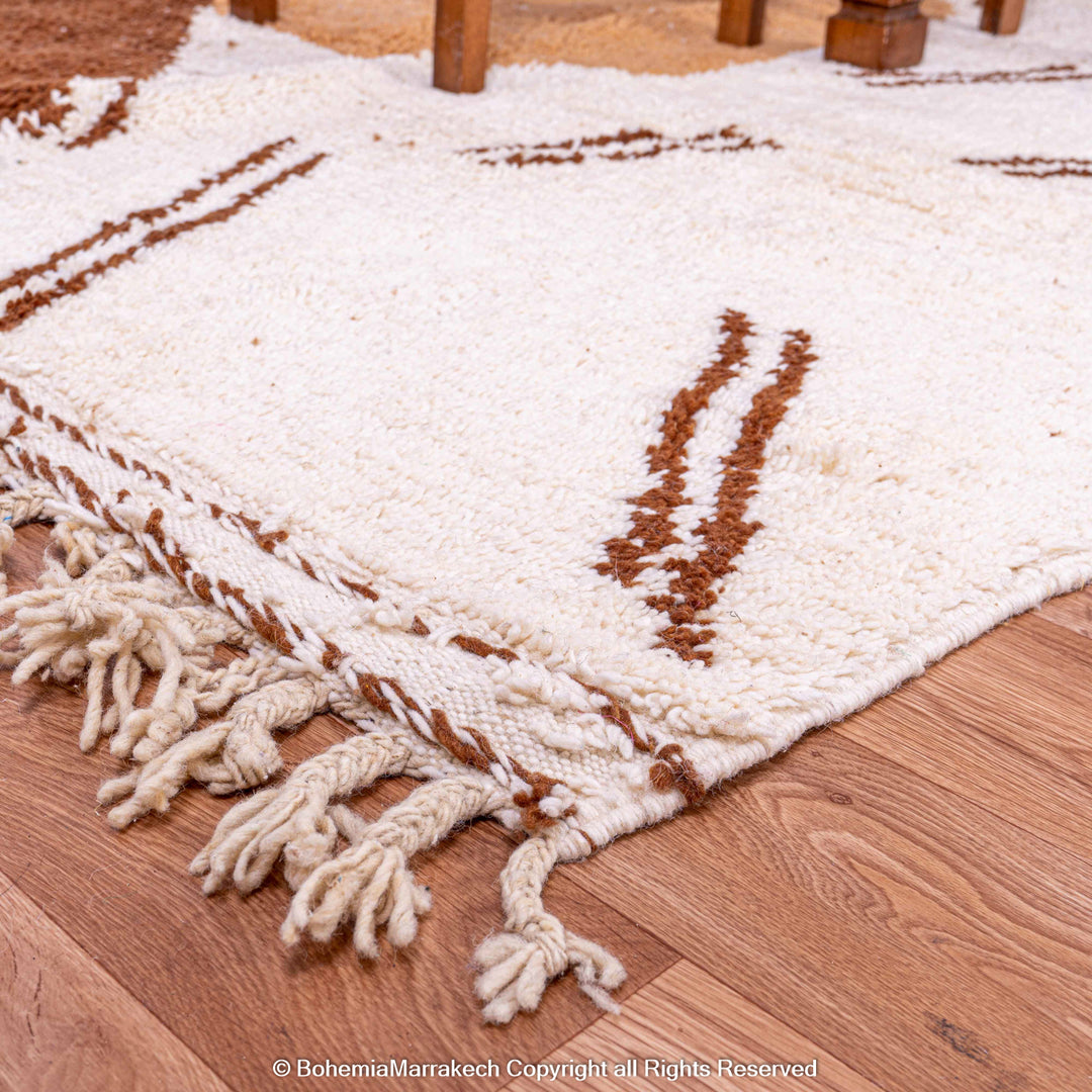 Modern Moroccan Berber rug with an abstract brown and beige design on a wooden floor. Handmade wool area rug from Morocco.