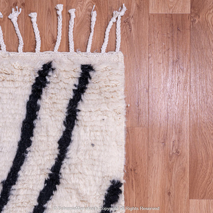 Black and White Beni Ourain Moroccan Wool Rug with Abstract Criss-Cross Patterns on a Wooden Floor