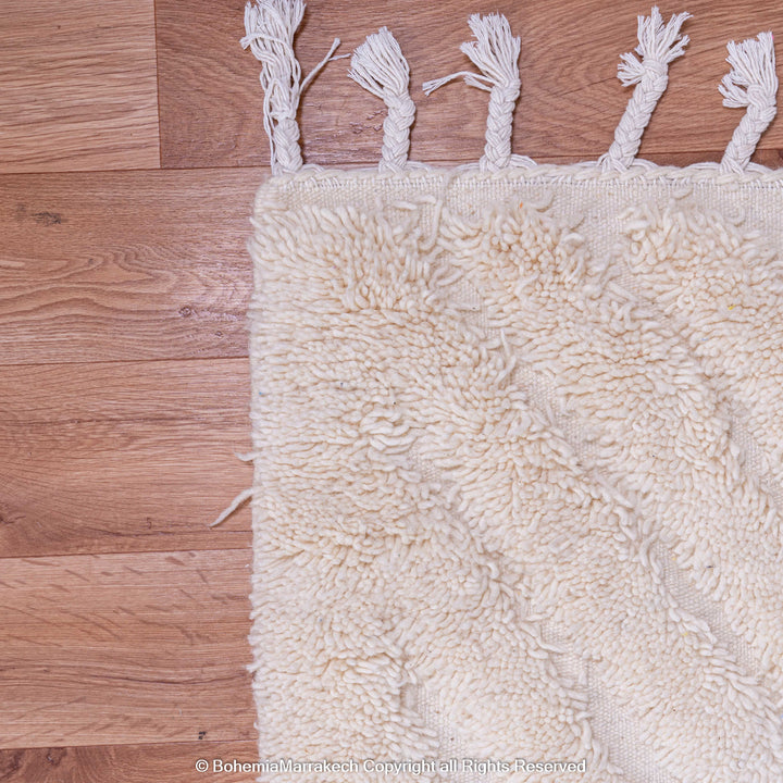 White Moroccan rug with subtle V texture on wooden floor, handmade wool rug from Morocco.