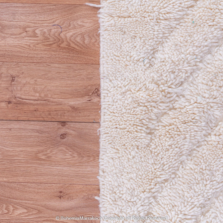 White Moroccan rug with subtle V-line texture on wooden floor. Perfect for minimalist and Scandinavian interiors.