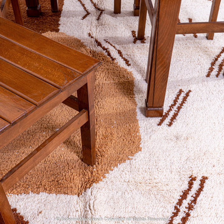 Modern Moroccan rug with abstract brown and beige design under wooden furniture in dining room.