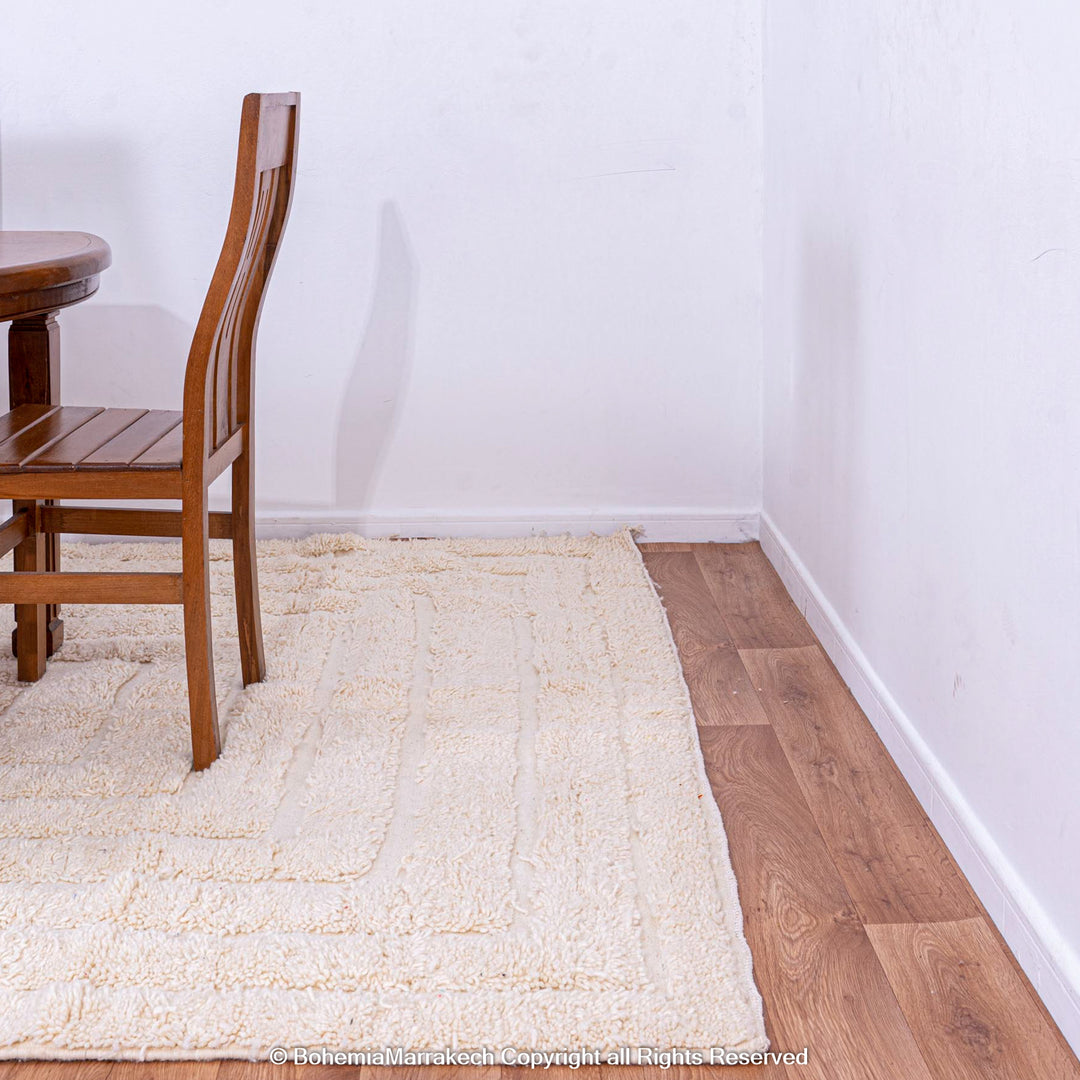 White Moroccan rug with subtle V line texture under wooden dining set on hardwood floor.
