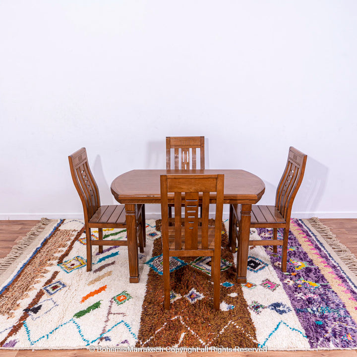 Colorful Moroccan wool Berber carpet with geometric patterns under wooden dining set, showcasing vibrant traditional design.