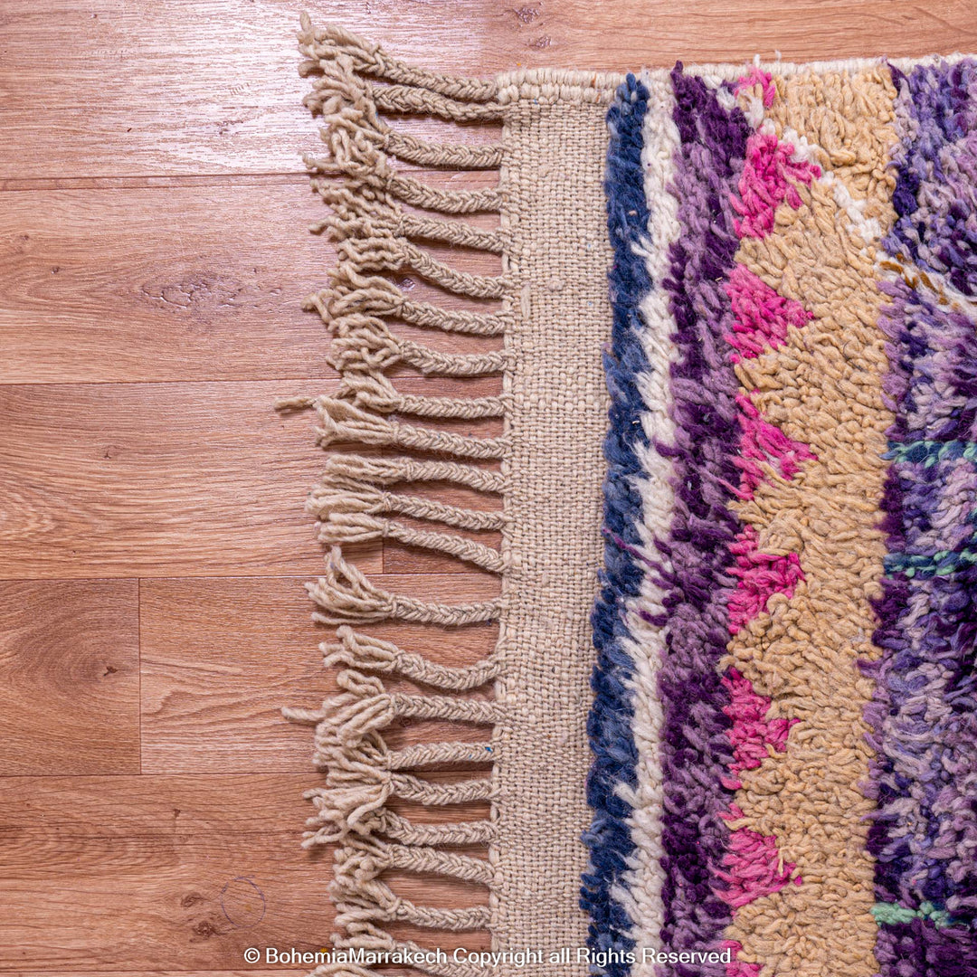 Vibrant handmade Moroccan Berber wool rug with colorful tribal patterns on a wooden floor.