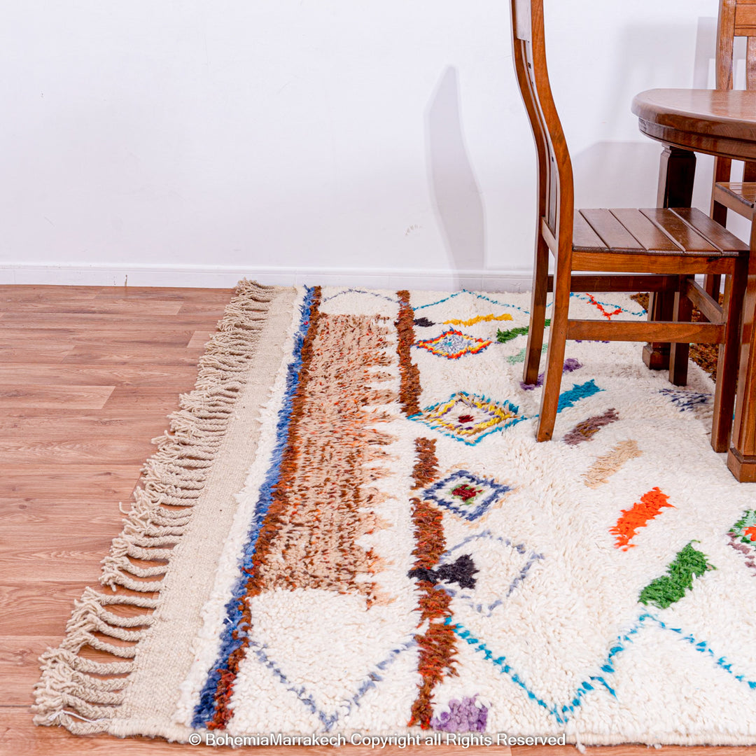 Handmade colorful Moroccan Berber rug with geometric and tribal motifs under dining set, showcasing unique wool texture.