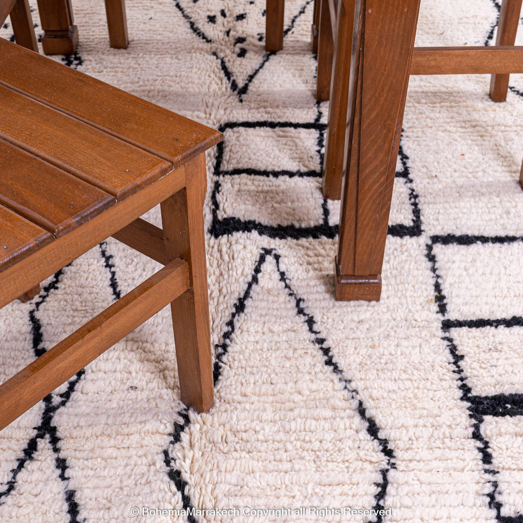 White Moroccan Rug with abstract diamond pattern under wooden dining chairs and table.