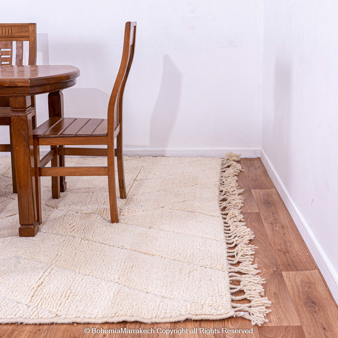 White Moroccan rug with zigzag pattern under wooden dining set, showcasing minimalist design and handwoven craftsmanship.